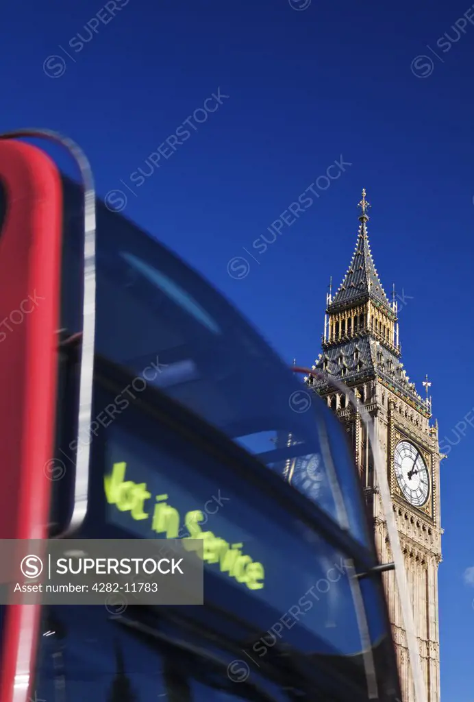 England, London, Westminster. A red double decker London bus going past Big Ben.