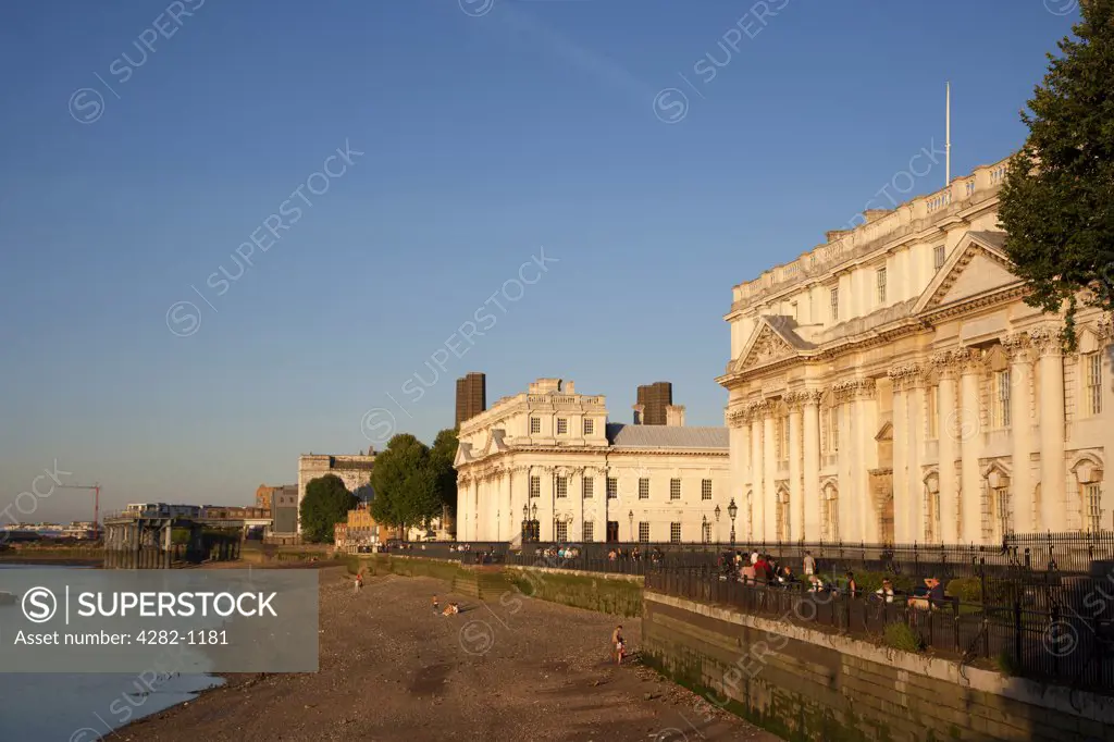 England, London, Greenwich. People walking past the Old Royal Naval College by the River Thames on a summer evening.