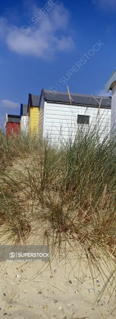 England, Suffolk, Southwold. Sand dunes and beach huts at Southwold.