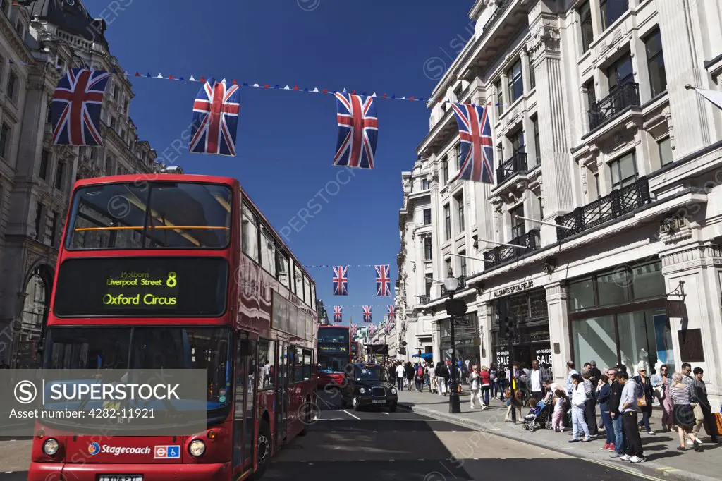 England, London, Regent Street. Red double decker buses and taxis travelling along Regent Street under red, white and blue bunting strung across the street to celebrate the Royal Wedding between Prince William and Catherine Middleton.