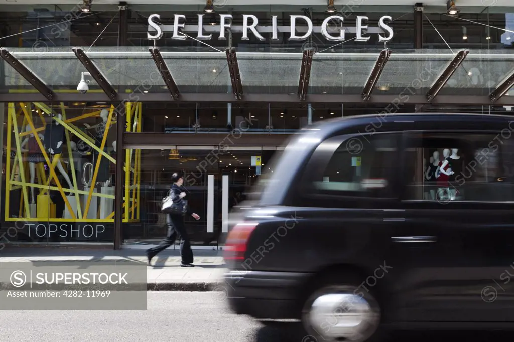 England, London, Oxford Street. A black London taxi cab passing the entrance to Selfridges in Oxford Street.