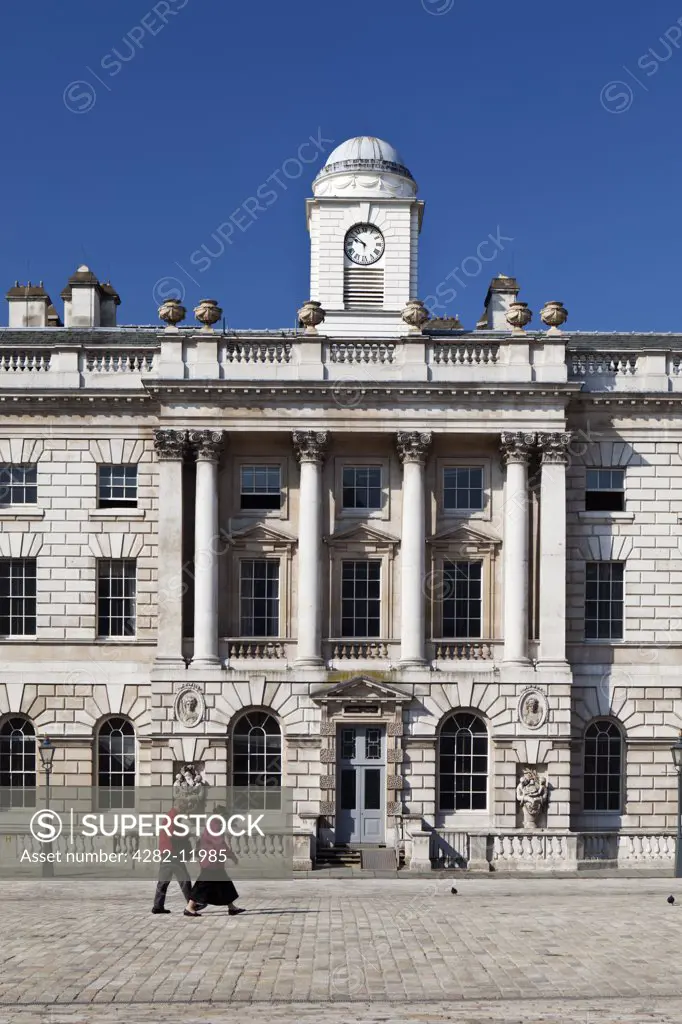 England, London, The Strand. A couple walking in the courtyard past the HM Revenue & Customs building at Somerset House.