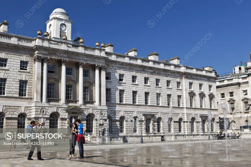 England, London, The Strand. A couple having their picture taken in the Edmond J. Safra Fountain Court of Somerset House.
