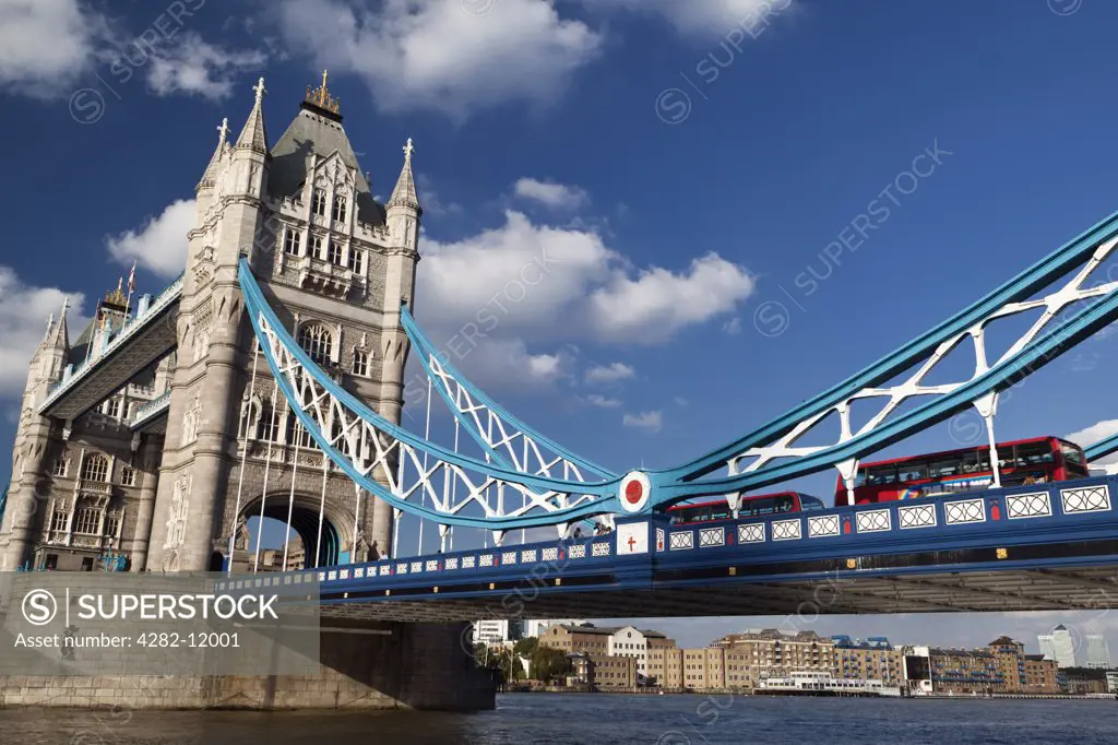 England, London, Tower Bridge. Red London buses crossing the River Thames over Tower Bridge, one of London's most famous and iconic landmarks.