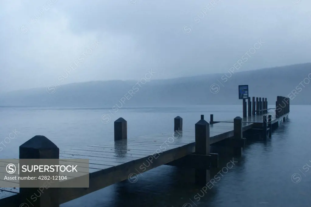 England, Cumbria, Coniston. A deserted jetty stretching out towards Coniston Water on a wet day on the Cumbria Way.
