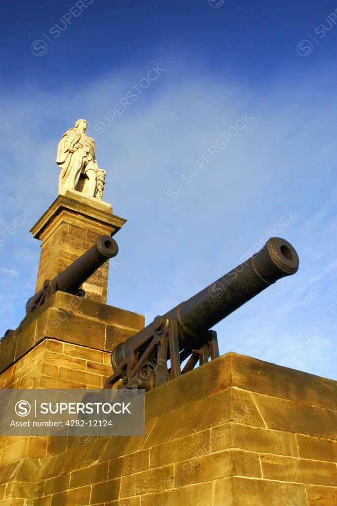 England, North Tyneside, Tynemouth. The setting sun iluminates the Collingwood monument and cannons.