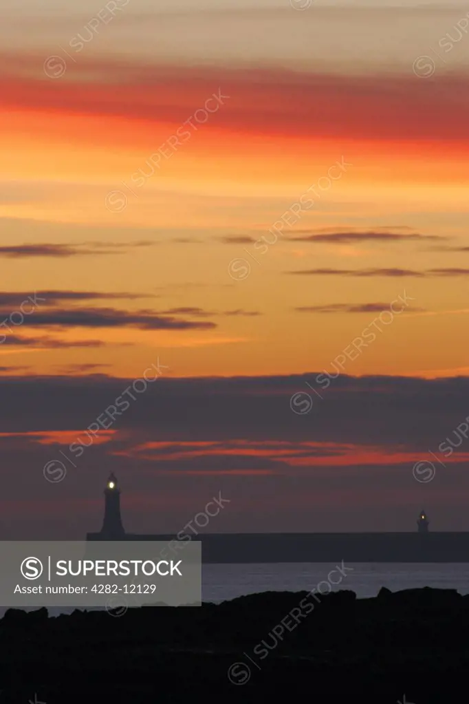 England, North Tyneside, Cullercoats. Sunrise looking towards the North Tyne Pier and lighthouse in Tynemouth.