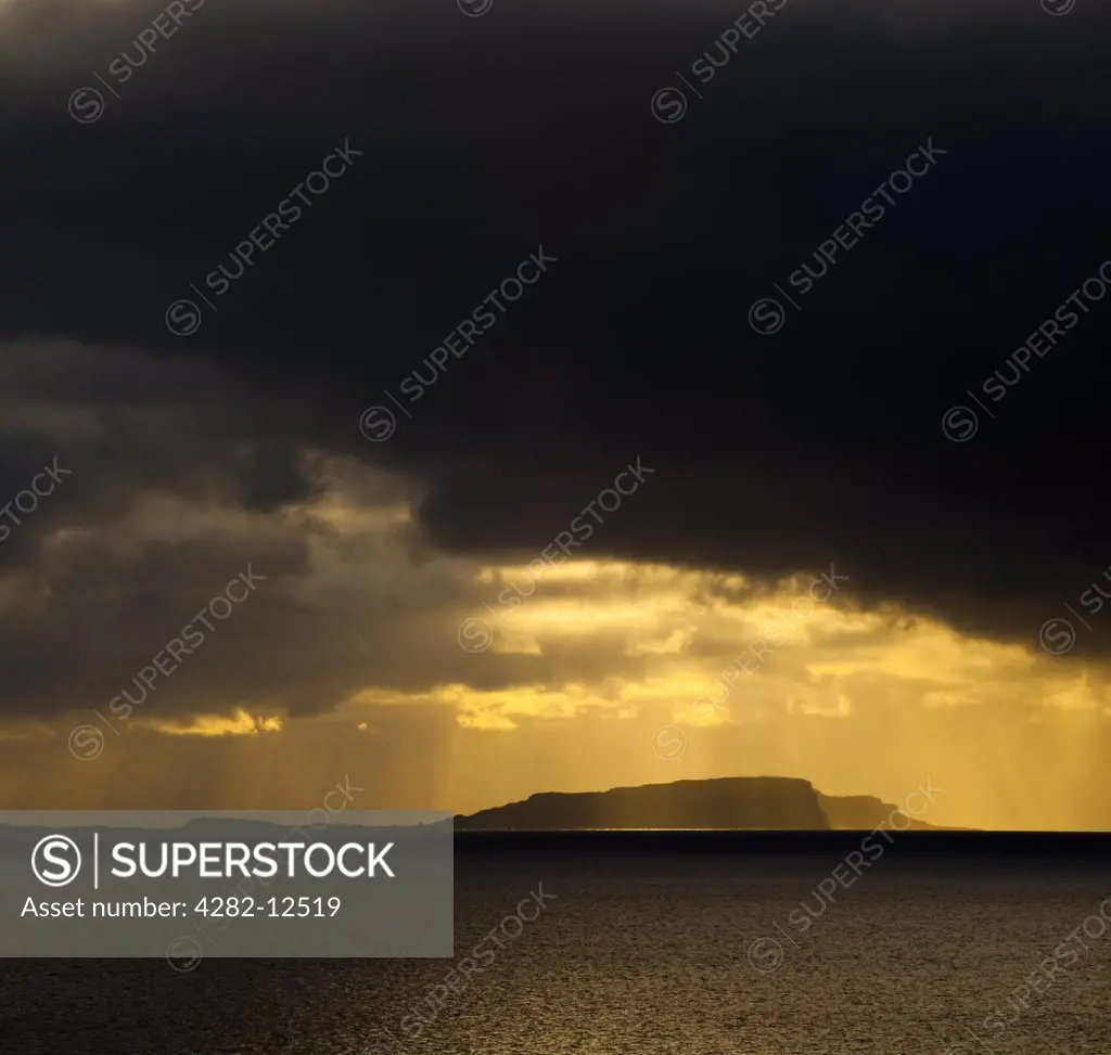 Scotland, Western Isles, Isle of Soay. Dramatic shafts of light from the setting sun above the Isle of Soay, viewed from Elgol on the Isle of Skye.
