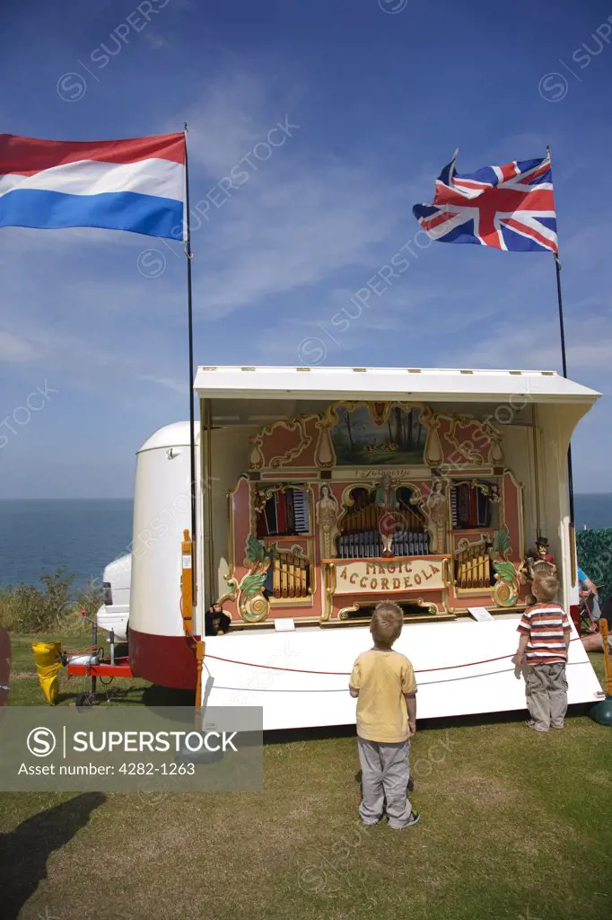England, Kent, Whitstable. Two young boys looking at a 41-key Heesbeen 'Magic Accordeola' fair organ by the seafront at a fair in Whitstable.