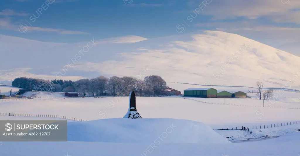Scotland, South Lanarkshire, Abington. A monument in honour of Matthew McKendrick, a former postmaster from Abington in Clydesdale, under the shadow of the snow covered Clyde Valley hills.