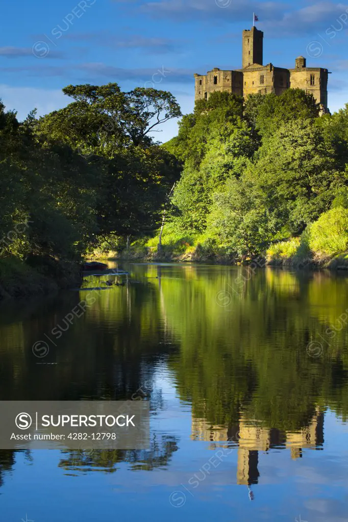 England, Northumberland, Warkworth. Warkworth Castle reflected in the still waters of the River Coquet.