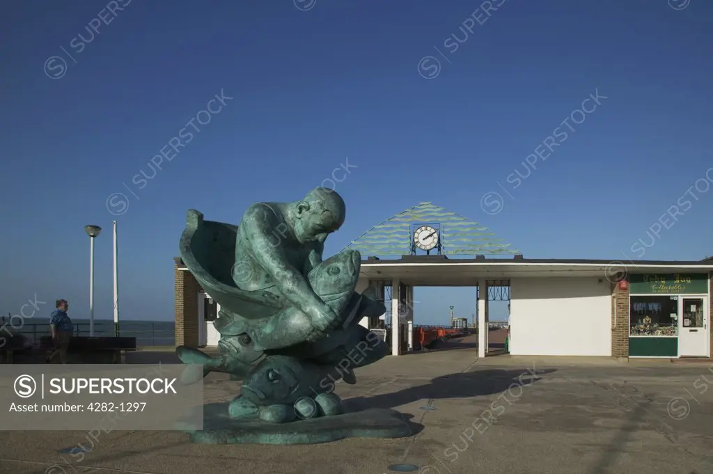 England, Kent, Deal. The statue of Alan Yates holding a giant Sea bass entitled ""Embracing the Sea"" by Jon Buck on Deal pier.