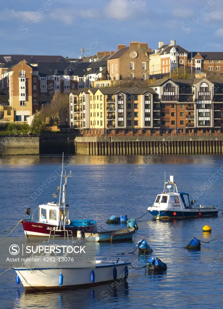 England, Tyne and Wear, North Shields. Boats moored on the River Tyne with a complex of new apartments located on the North Shields Quayside in the distance.