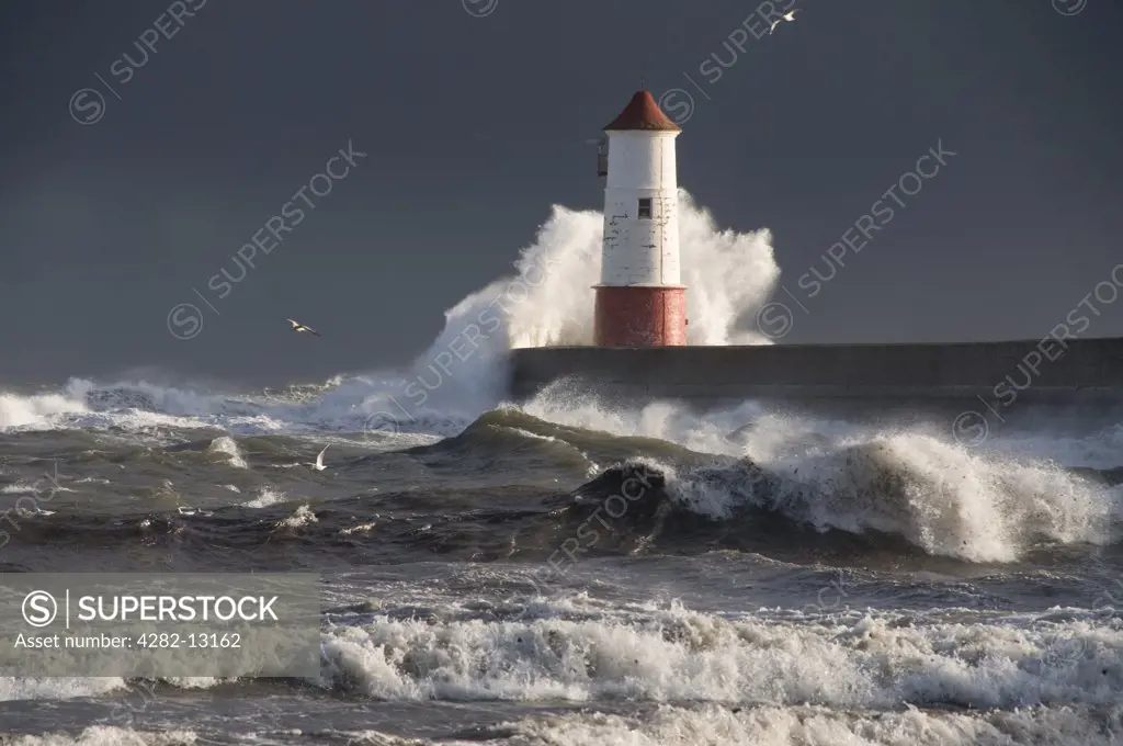 England, Northumberland, Berwick upon Tweed. Large waves crashing around Berwick Lighthouse at the end of the pier in Berwick upon Tweed.