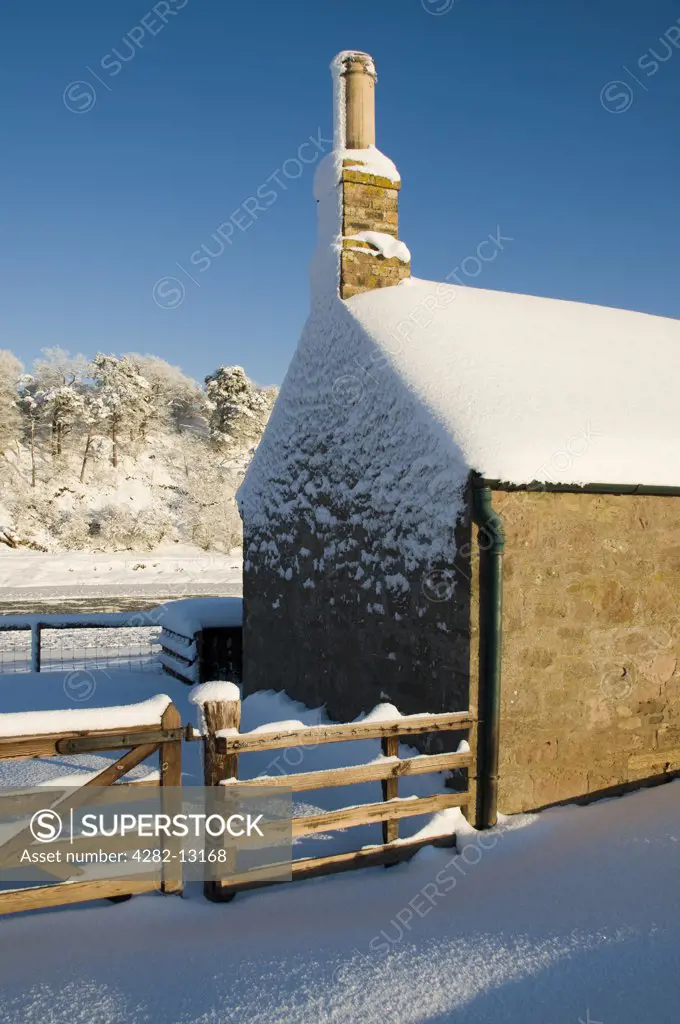 Scotland, Scottish Borders, Ladykirk. The gable end of the Sands Shiel on the River Tweed covered by a winter snowfall.