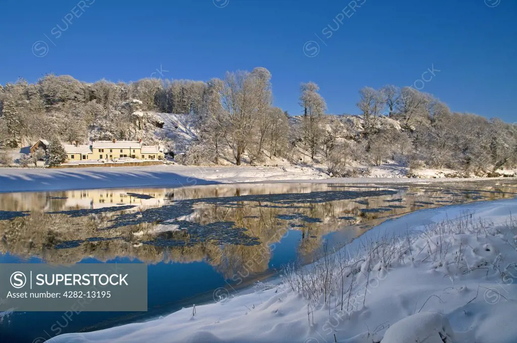 England, Northumberland, Norham. Norham Boathouse in a winter landscape reflected in the River Tweed marking the border between Scotland and England.