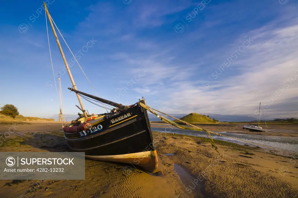 England, Northumberland, Alnmouth. A sailing boat beached in the River Aln estuary at Alnmouth on the North East coast of England looking towards Church Hill.