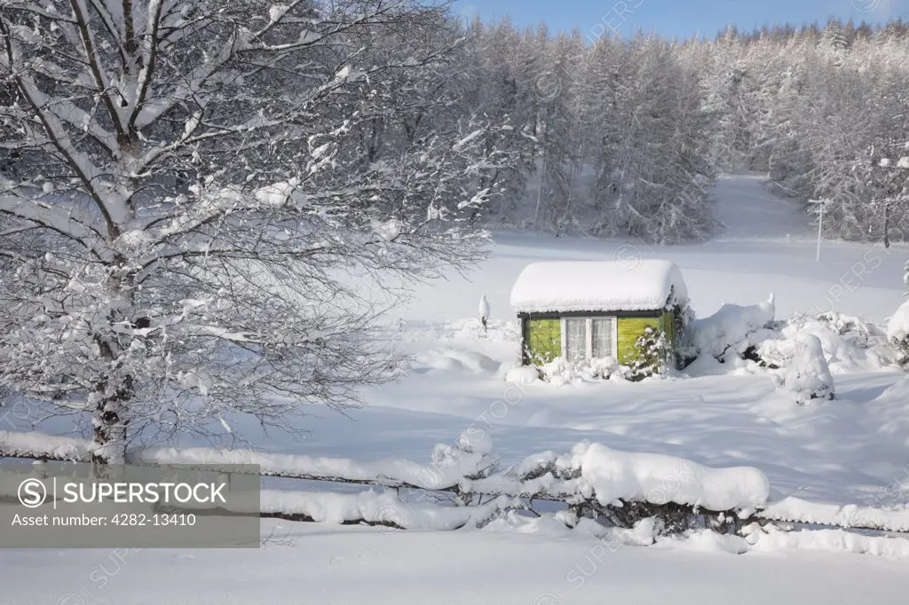 Scotland, Aberdeenshire, Strathdon. A view toward a Strathdon garden and shed in winter snow.