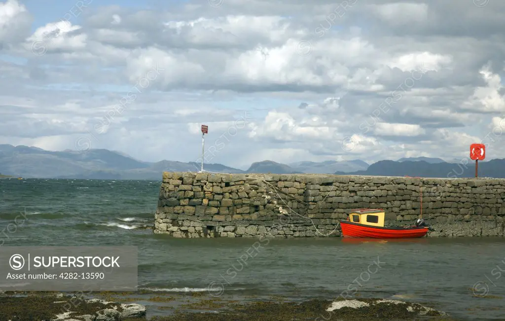 Scotland, Highland, Broadford. A small red boat moored by the harbour wall at Broadford on the Isle of Skye.