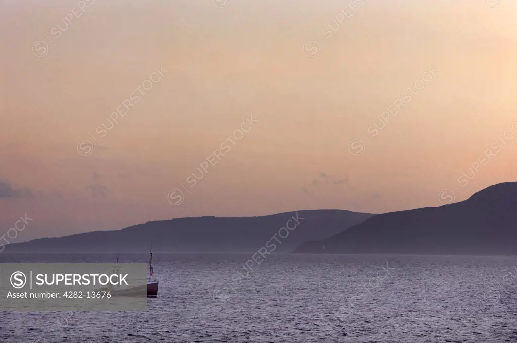 Scotland, North Ayrshire, Isle of Arran. A fishing Boat in dawn light off the coast of the Isle of Arran.