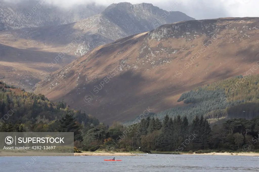 Scotland, North Ayrshire, Goat Fell. Kayaking on the sea against the dramatic backdrop of Goat Fell, the highest point on the Isle of Arran.