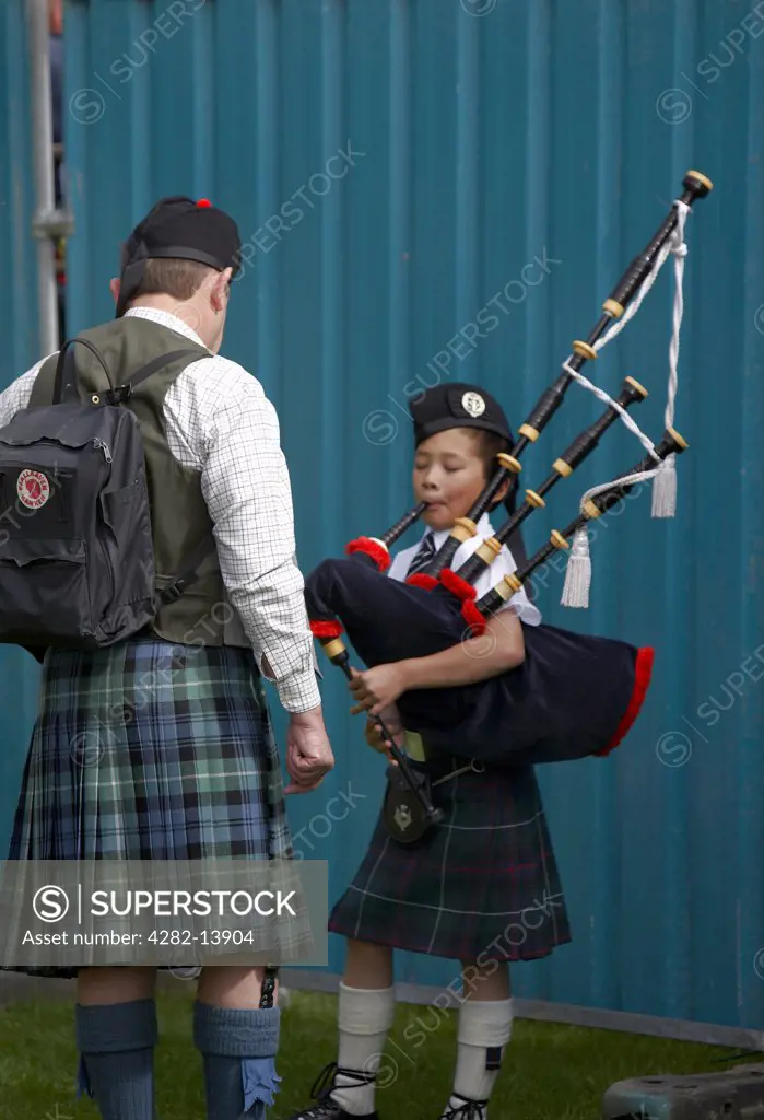 Scotland, Aberdeenshire, Strathdon. A young piper practising at the Lonach Highland Games.