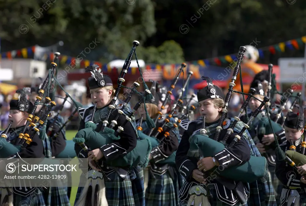 Scotland, Aberdeenshire, Strathdon. Pipers in a marching band performing at the Lonach Highland Games.