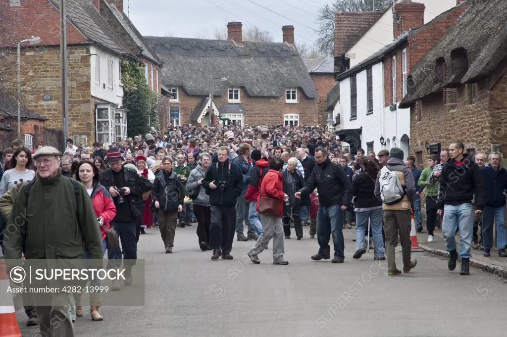 England, Leicestershire, Hallaton. Crowds parade through the village of Hallaton for the traditional Easter Monday Bottle-kicking event.