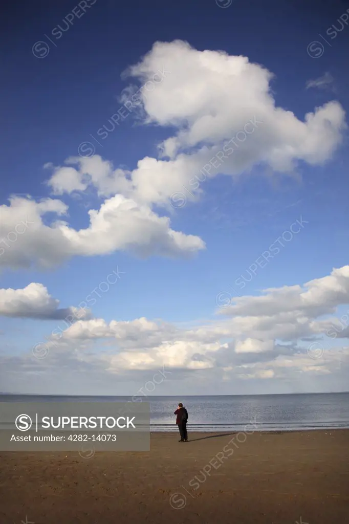 Scotland, Midlothian, Edinburgh. A man looking out to sea on Portobello Beach in Edinburgh.