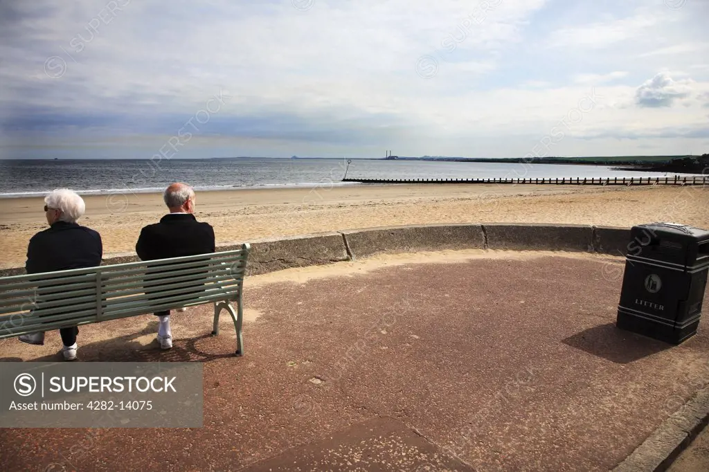 Scotland, Midlothian, Edinburgh. A couple sitting on the promenade at Portobello Beach in Edinburgh.