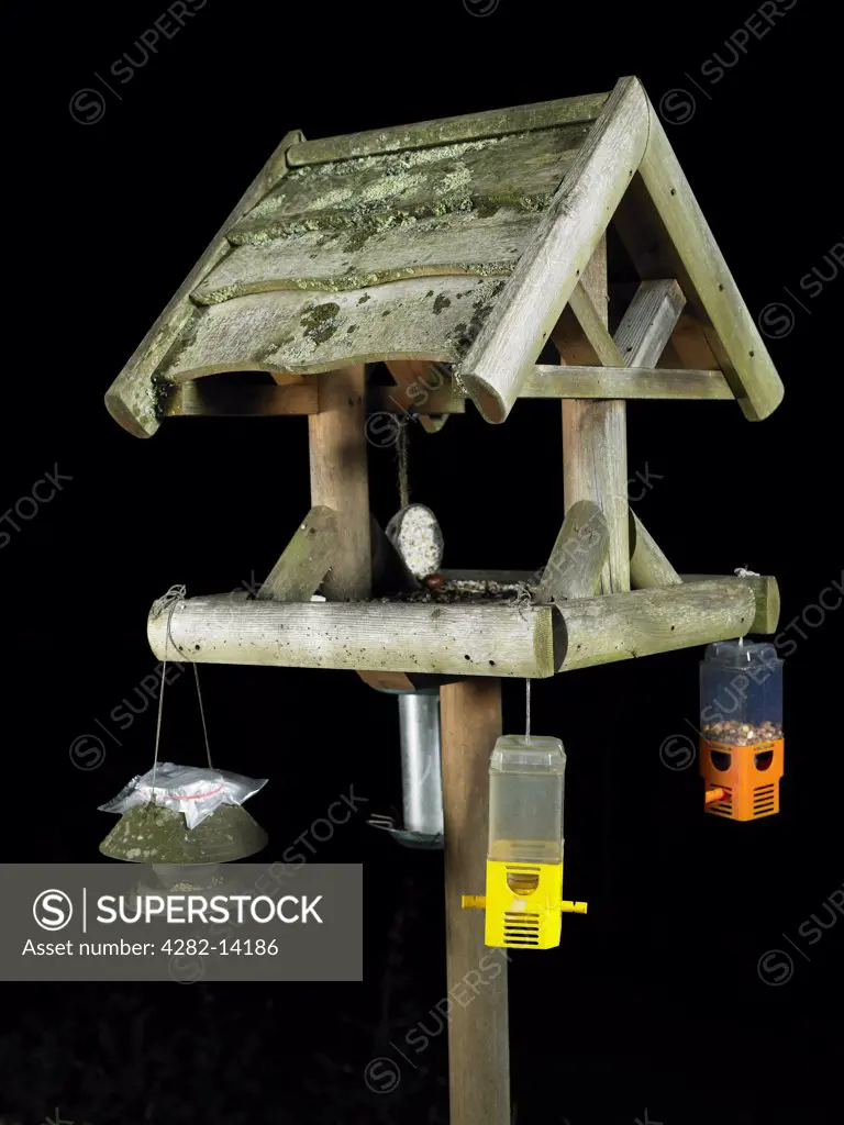 England, Channel Islands, Guernsey. A bird table with various bird feeders hanging from it in Guernsey.