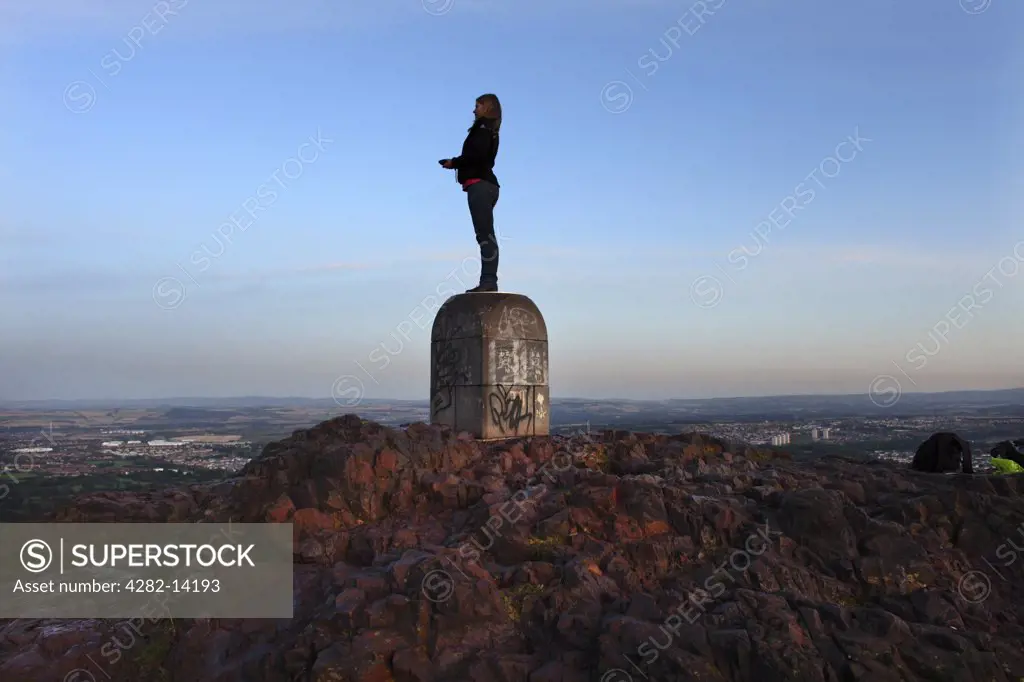 Scotland, City of Edinburgh, Edinburgh. A woman standing on top of Arthur's Seat to take in the view over the city of Edinburgh.