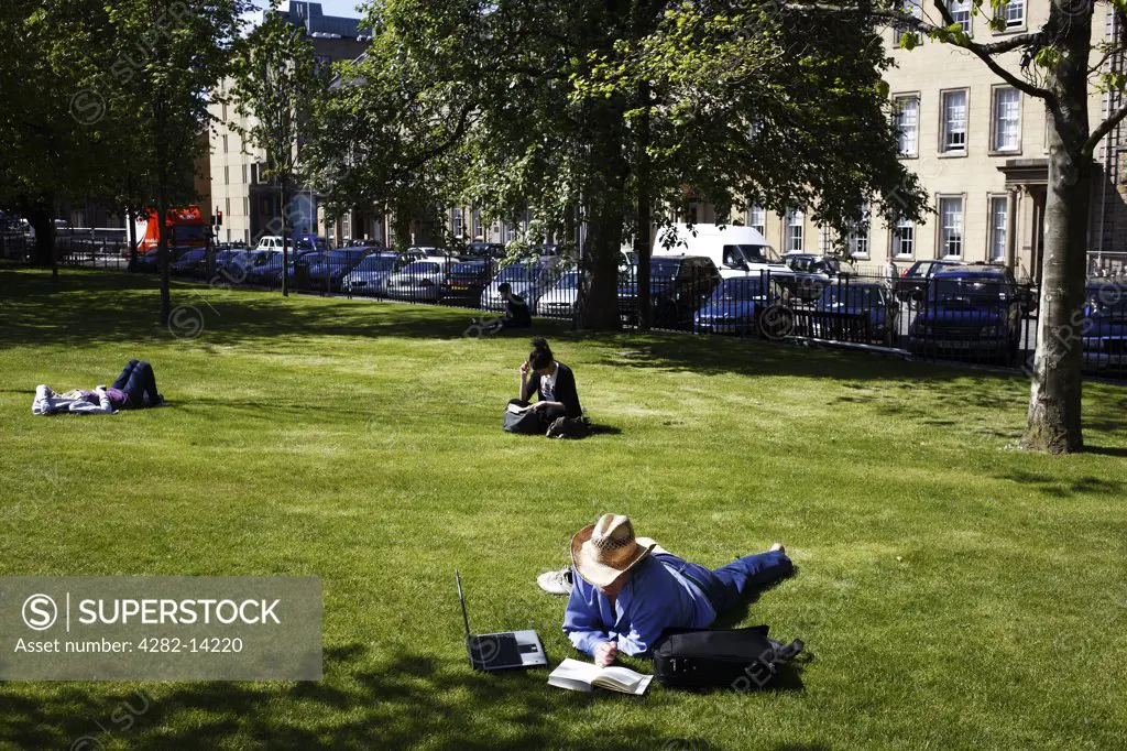 Scotland, City of Edinburgh, Edinburgh. People relaxing in the sunshine in St. Andrew Square.