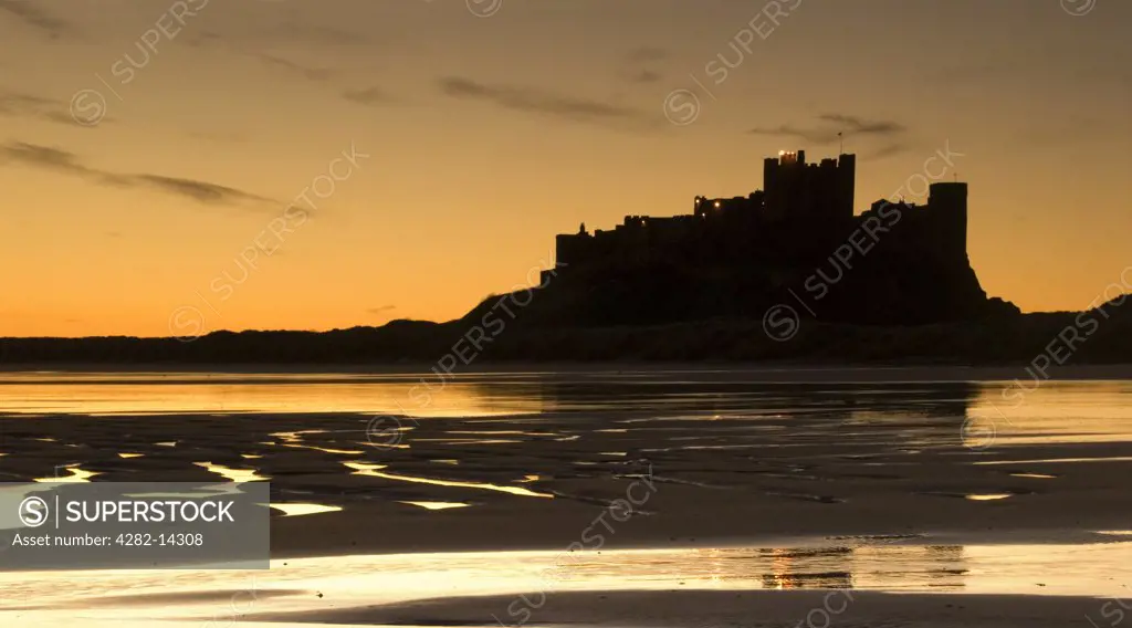 England, Northumberland, Bamburgh. Bamburgh Castle in silhouette at dawn.
