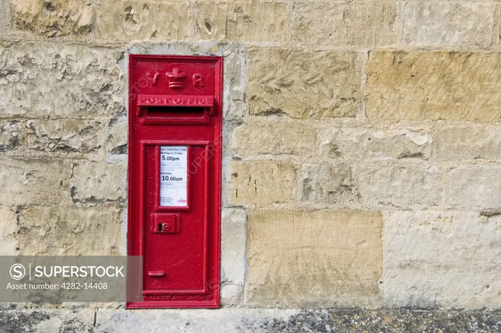 England, Gloucestershire, Chipping Camden. A classic red letter box set into a sandstone wall in Chipping Camden.