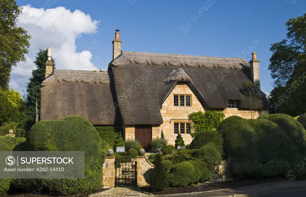 England, Gloucestershire, Chipping Camden. Hedges surround a traditional thatched cottage at Chipping Camden in Gloucestershire.