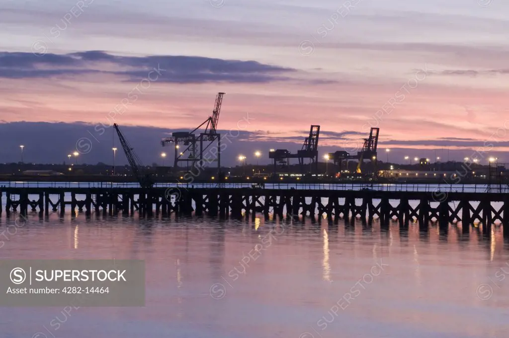 England, Suffolk, Harwich. A view towards an illuminated Harwich docks from Shotley Gate at sunset.