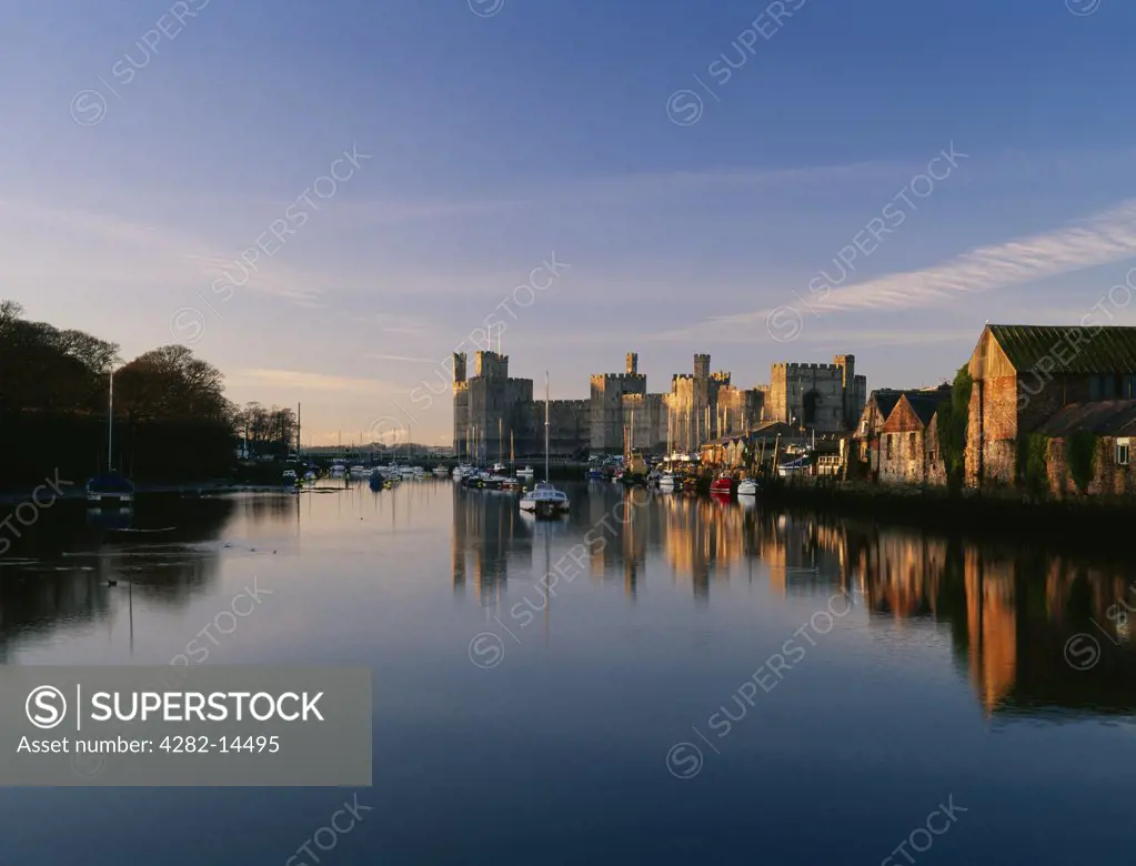 Wales, Gwynedd, Caernarfon. Looking NW along the River (Afon) Seiont at high tide with Slate Quay and Caernarfon Castle dappled by winter sunshine. The castle stands at the point where the river flows into the Menai Strait.