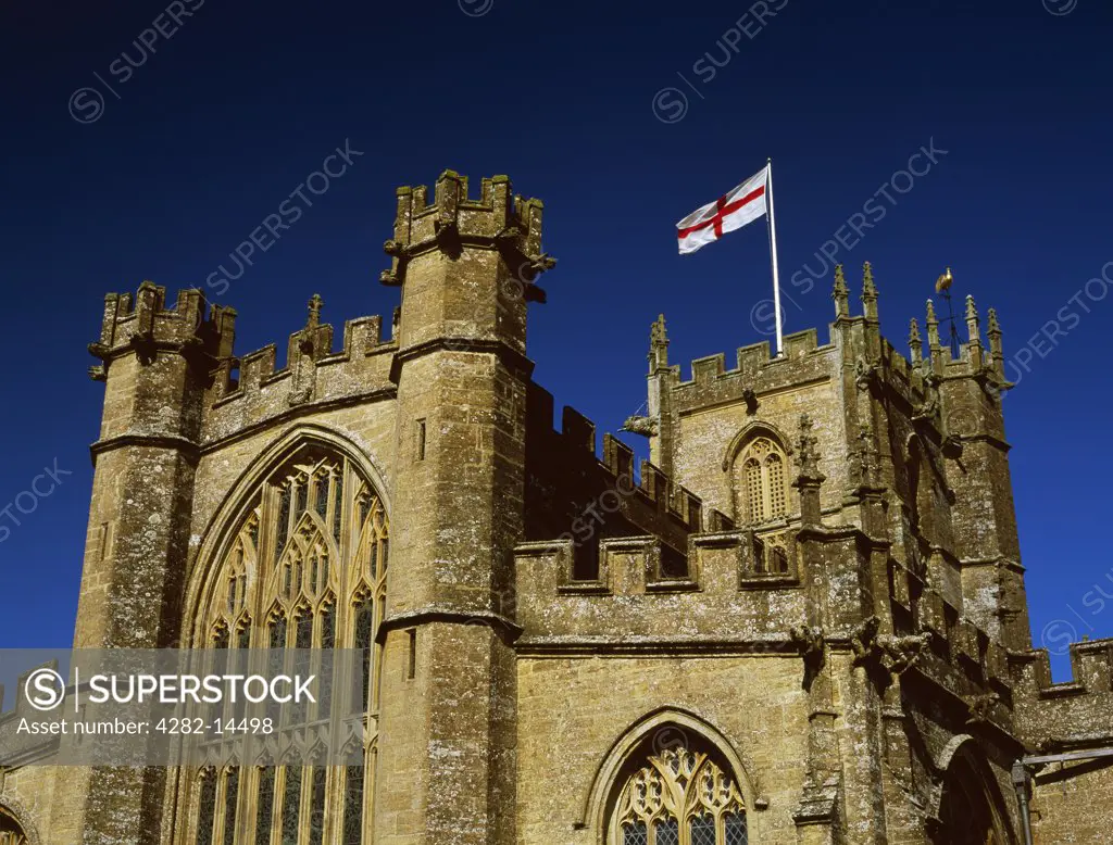 England, Somerset, Crewkerne. Flag of St George - red cross on a white background - flying from the tower of St Bartholomew's late Medieval church which was originally founded as a Saxon minster.