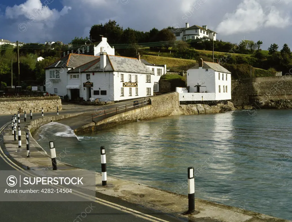 England, Cornwall, Portmellon. Early morning sunshine illuminates the Rising Sun Inn and Rock Cottage in Portmellon cove between Chapel Point and Mevagissey near St Austell.