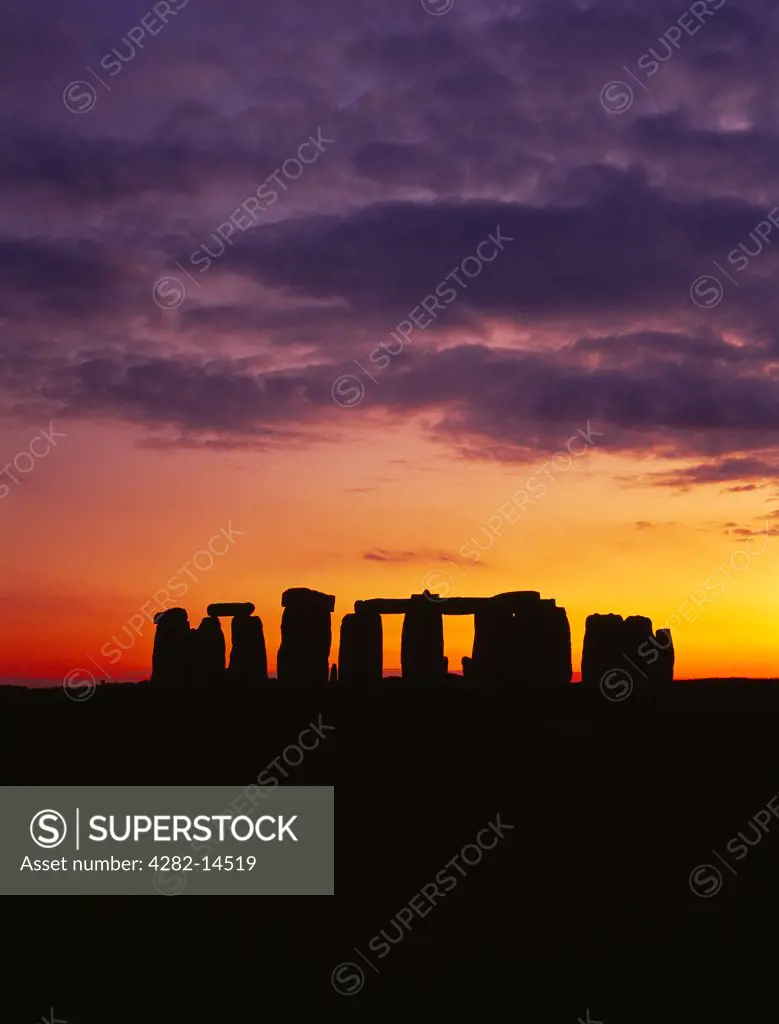 England, Wiltshire, Stonehenge. The Stonehenge trilithons silhouetted after sunset.