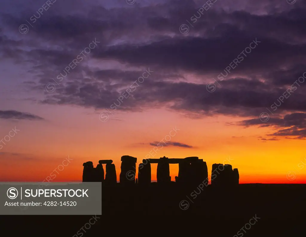 England, Wiltshire, Stonehenge. The Stonehenge trilithons silhouetted after sunset.