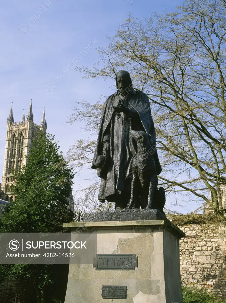 England, Lincolnshire, Lincoln. Cast bronze by George Frederick Watts of poet laureate Alfred, Lord Tennyson in Minster Yard with one of Lincoln cathedral's western towers visible in the background.