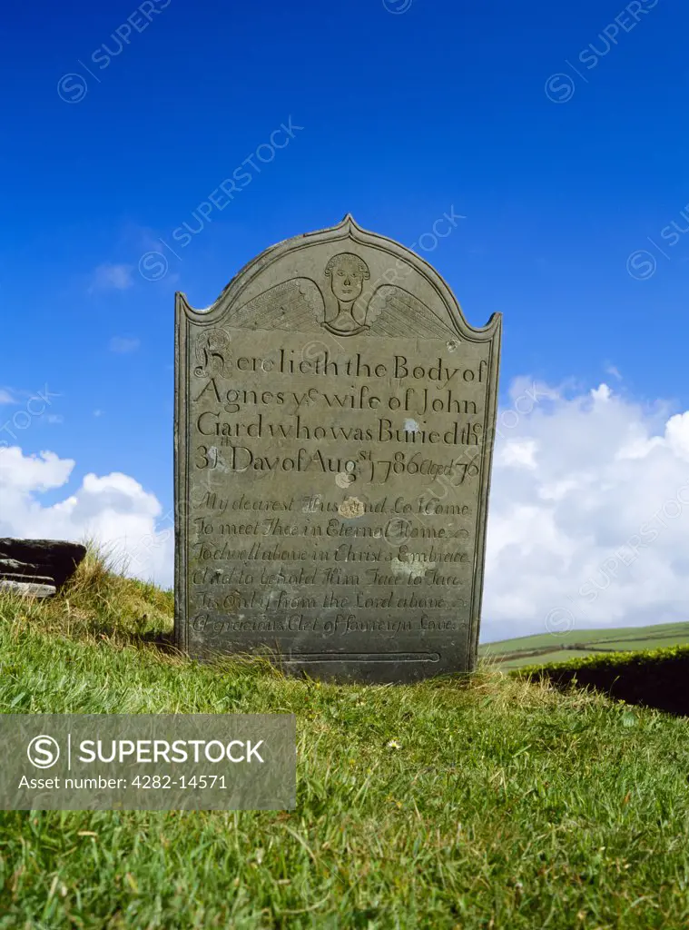 England, Cornwall, Forrabury. A Georgian headstone, decorated with an angel, stands beside the path to St Symphorian's church on Forrabury Common above Boscastle harbour.
