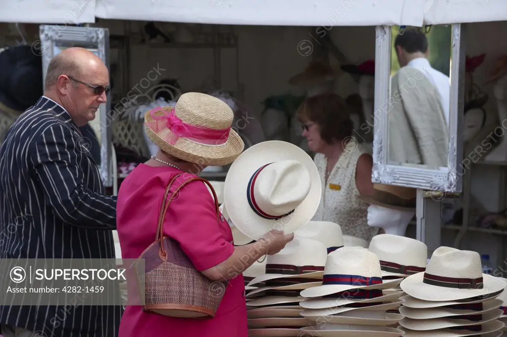 England, Oxfordshire, Henley-on-Thames. A couple looking at Panama hats for sale at the annual Henley Royal Regatta.