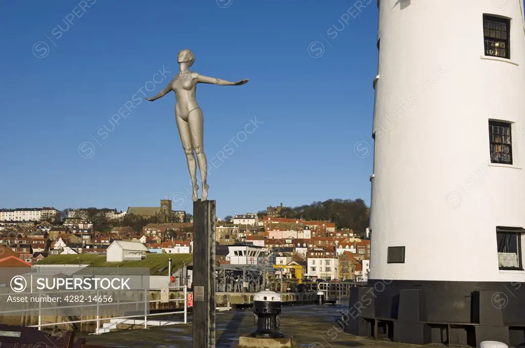 England, North Yorkshire, Scarborough. The Diving Belle sculpture representing Scarborough of the present by Craig Knowles next to Scarborough Lighthouse on Vincent Pier.