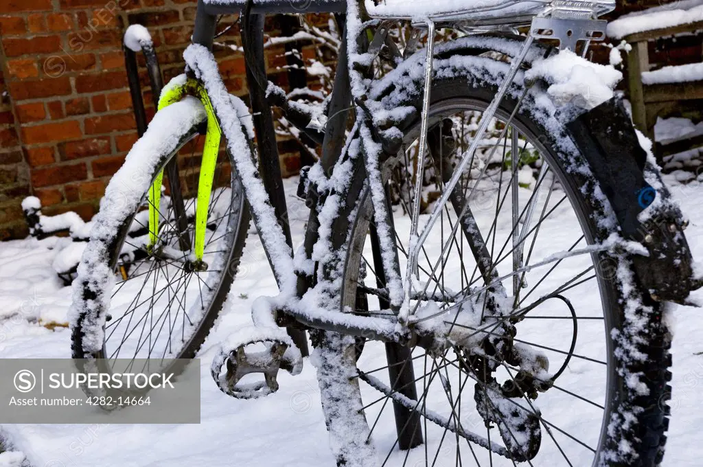 England, North Yorkshire, York. A snow covered bicycle locked to a bike rack in York.
