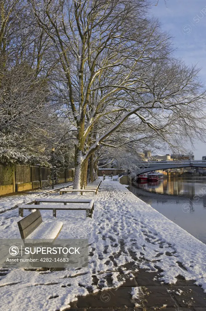 England, North Yorkshire, York. Snow covering the banks of the River Ouse with Lendal Bridge in the background in winter.