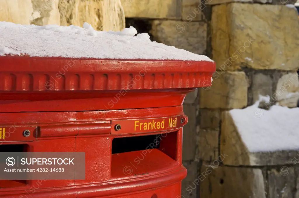England, North Yorkshire, York. A red post box with a dusting of snow on top in York.