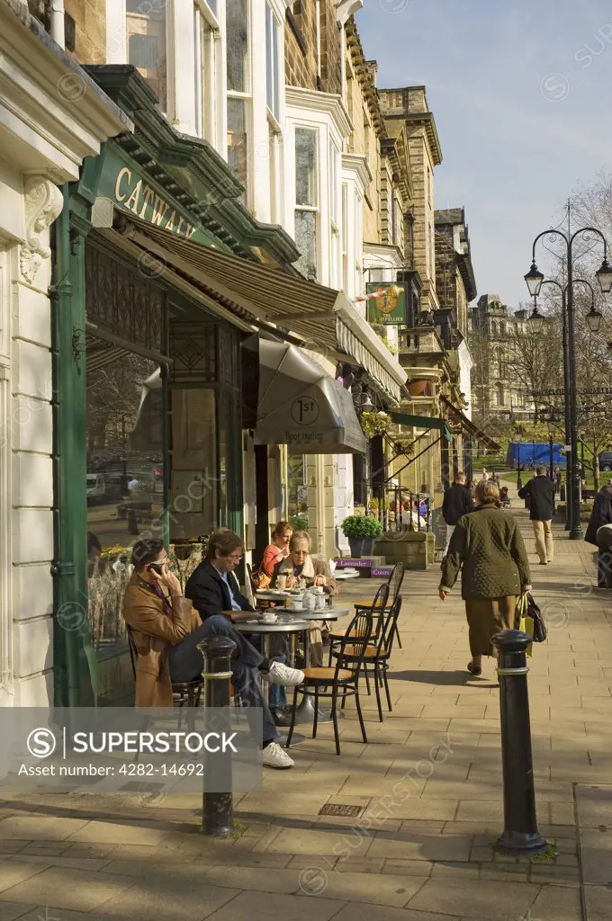 England, North Yorkshire, Harrogate. People sitting outside a cafe enjoying the spring sunshine on Montpellier Parade.